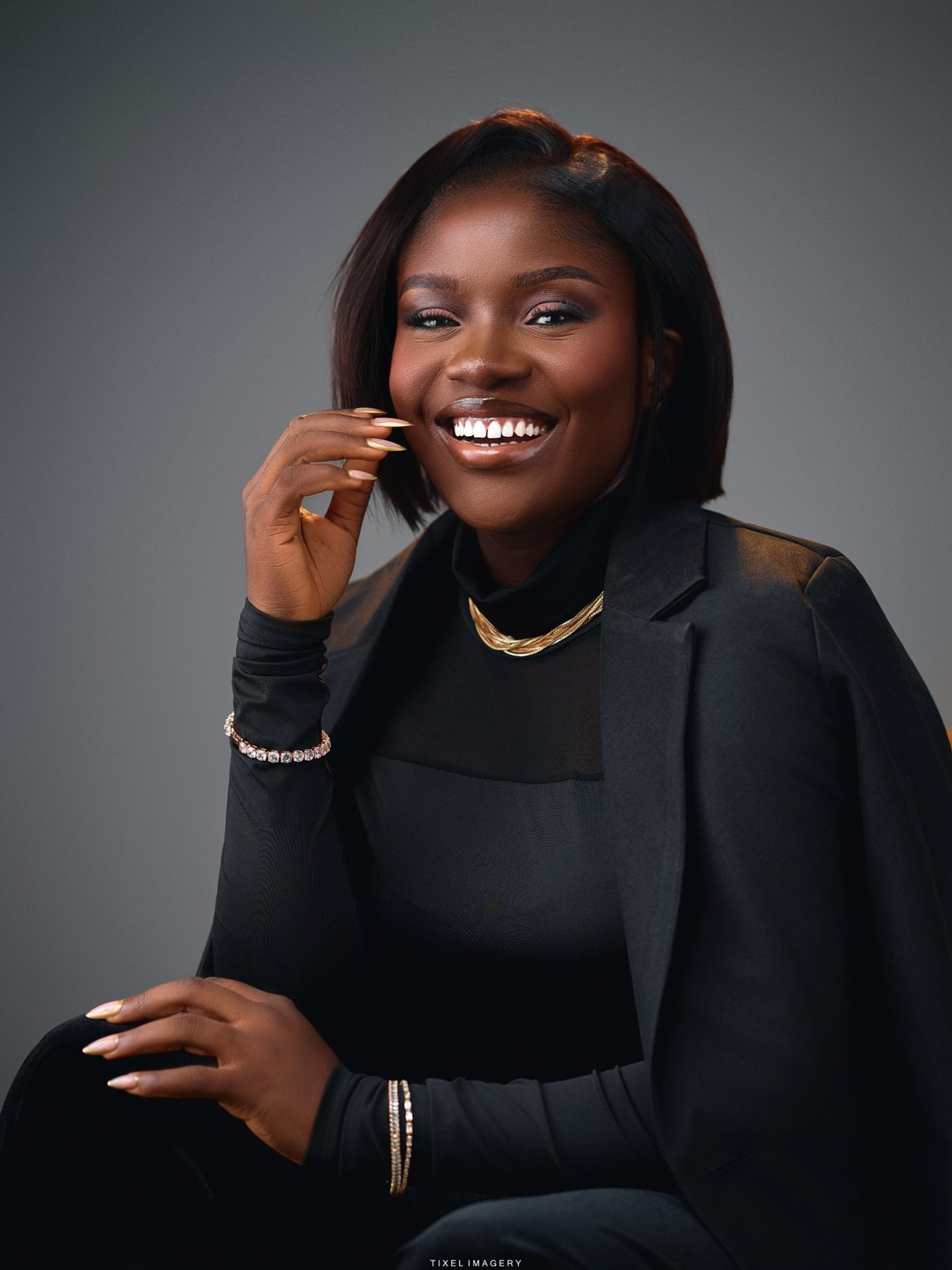 Sarah Adesemoye smiling, in a black blazer and gold necklace.