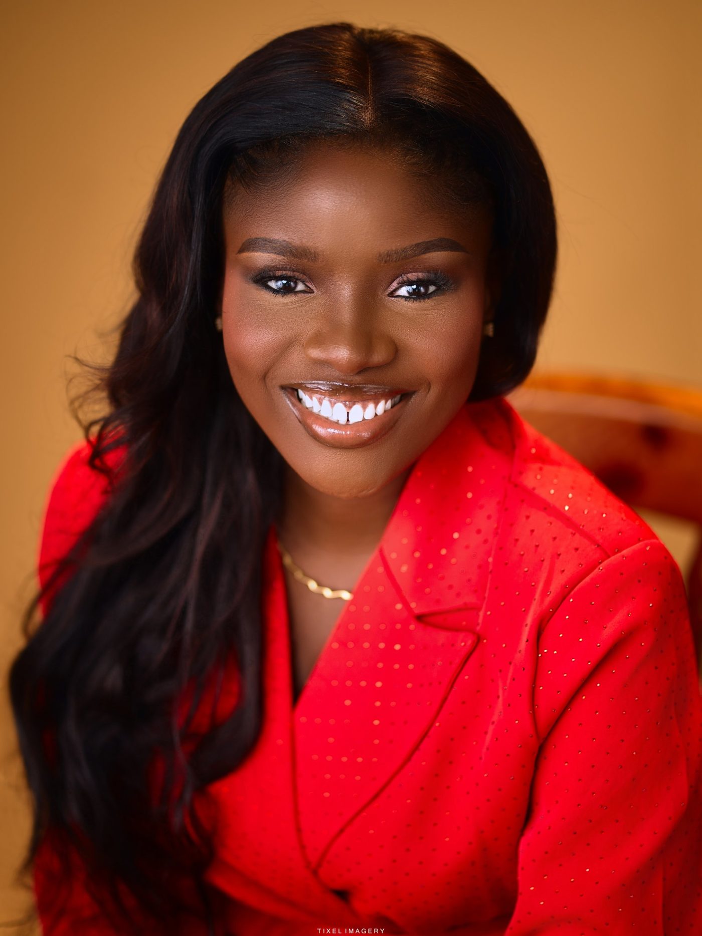 Sarah Adesemoye, global business speaker, smiling in a red blazer.